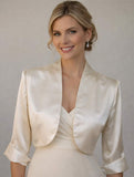 Woman wearing a ivory satin jacket over a dress against a plain background