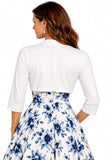 A woman shown from the back wearing a white three-quarter sleeve cropped jacket layered over a white skirt with a blue floral print, against a plain white background.