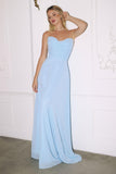 Woman wearing a light blue strapless gown against a white wall.